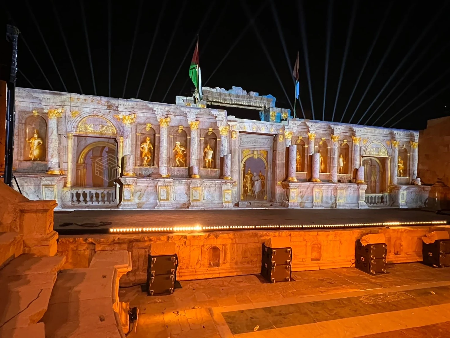 Wide nighttime photograph of architectural projection mapping with illuminated sculptures and details across the historic Northern Theatre facade at Jerash Festival 2025